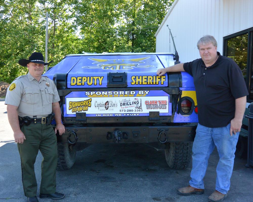 Two men take photos in front of the Deputy Sheriff's jeep.