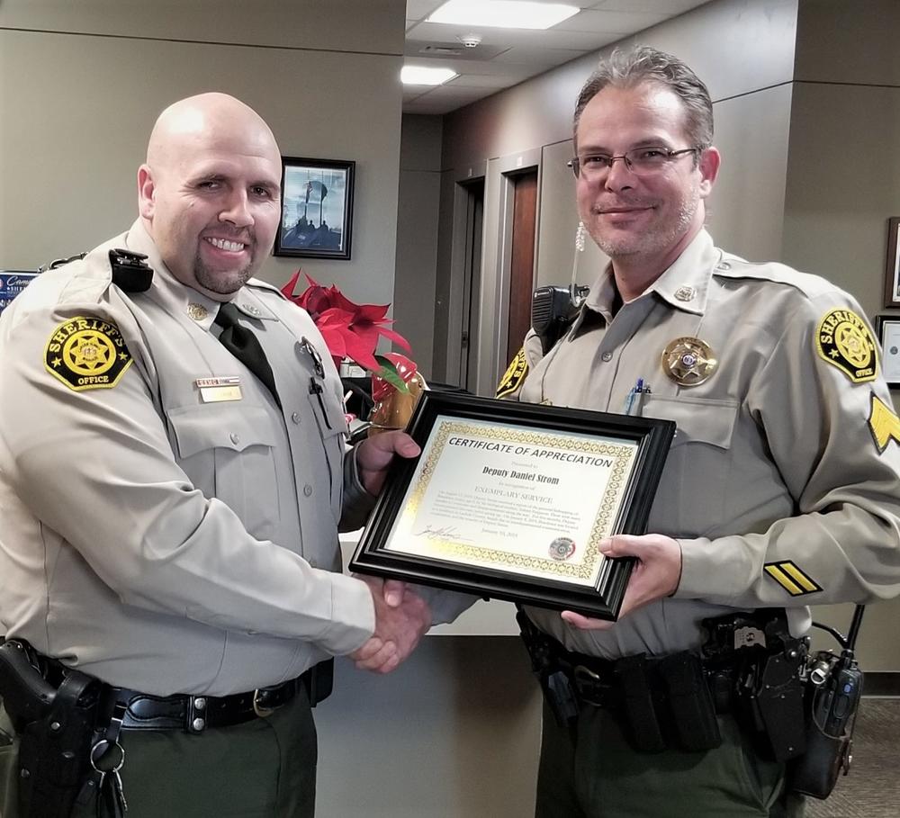Deputy Strom and Sergeant Dziadosz holding a certificate together.