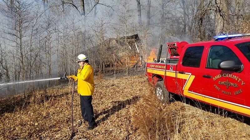 A firefighter putting out a fire in the woods.