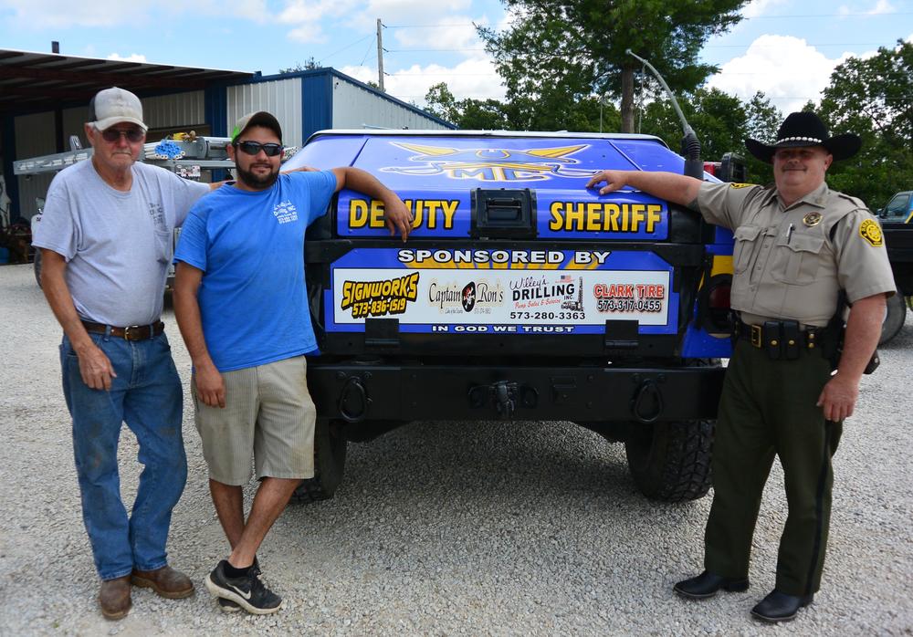 Deputies taking a photo in front of the Deputy Sheriff's jeep.