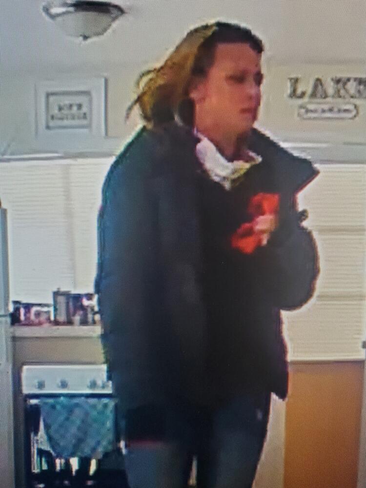 Burglary suspect 2. Woman in a black jacket hiding items.